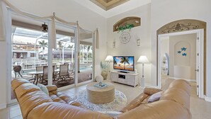 Een woonkamer met een groot raam, een televisie en een zithoek met een ronde salontafel.