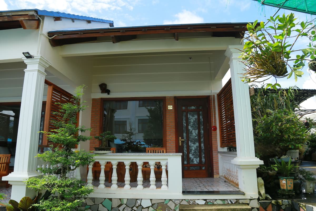 A building with a covered porch, a wooden door, and potted plants.