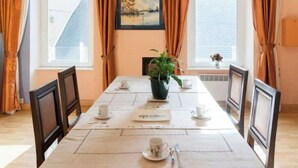 Ein Essbereich mit einem Tisch für vier Personen, einschließlich eines Topfpflanzens, einem gerahmten Bild an der Wand und einem Fenster mit Vorhängen.