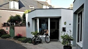 Ein modernes Gebäude mit weißer Fassade, einem Fahrrad davor und einem Blumentopf.
