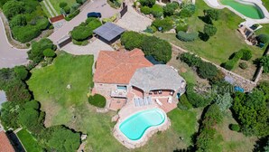 Vue aérienne d’une propriété résidentielle dotée d’une piscine, d’un patio couvert et d’une pelouse bien entretenue.