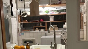 Cuina amb un rentaplat, una taula de tallar i un bol d'albercocs.