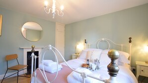 A neatly arranged bedroom with a bed, bedside tables, a chair, and a mirror on the wall. - 11 Crabbe Street, Aldeburgh (Aldeburgh)