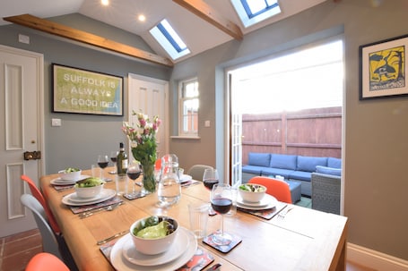 A dining area with a wooden table set for a meal, a vase with flowers, and a framed quote on the wall.