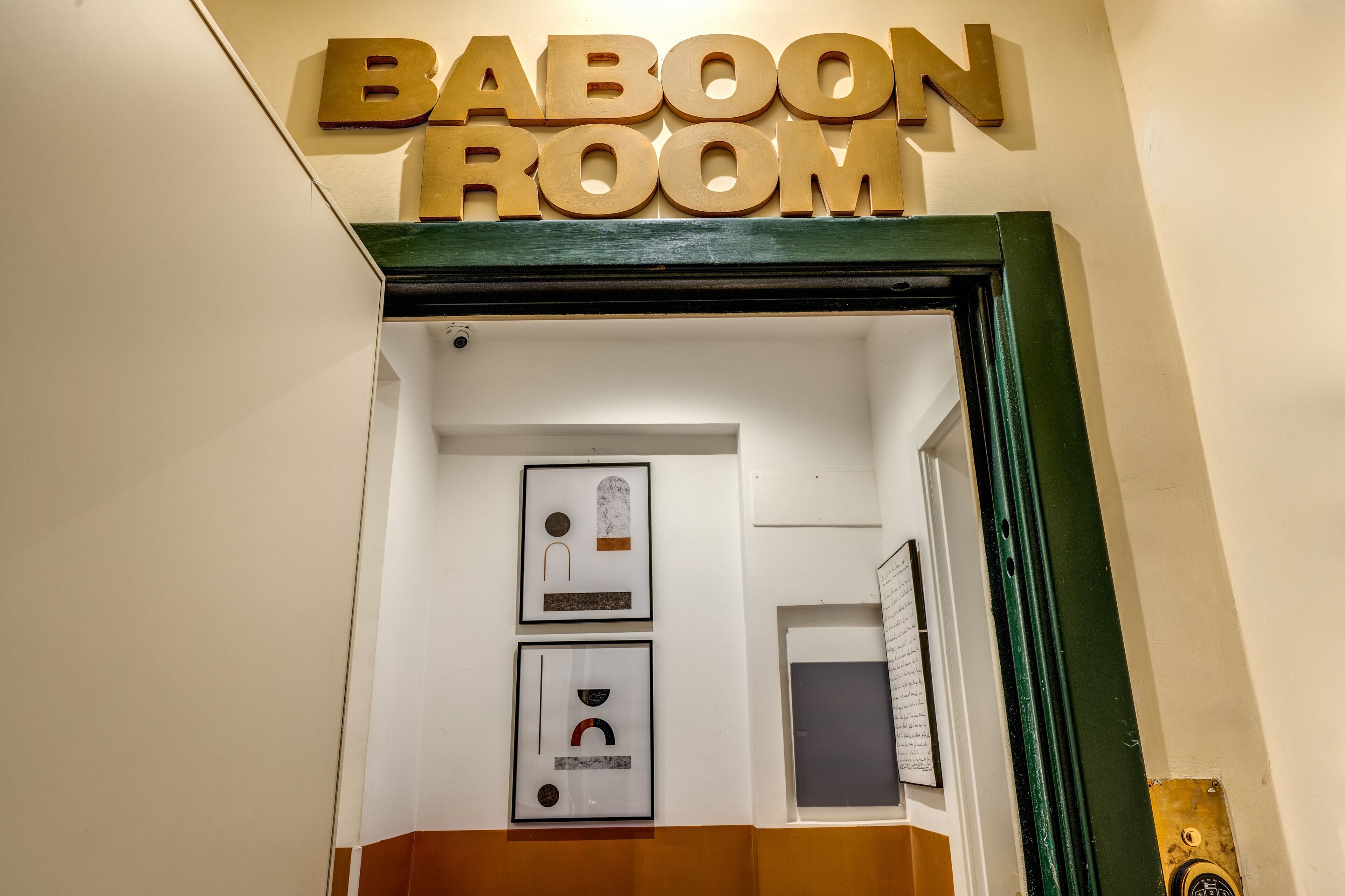 Una puerta con un letrero que dice 'BABOON ROOM' y dos cuadros en la pared.