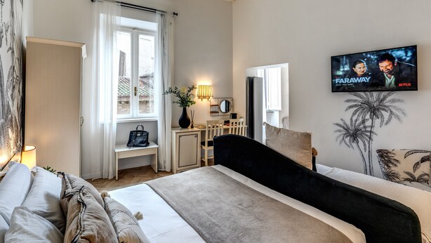 A bedroom with a bed, a desk, a TV, and a window with curtains. - Baboon Room (Rome)