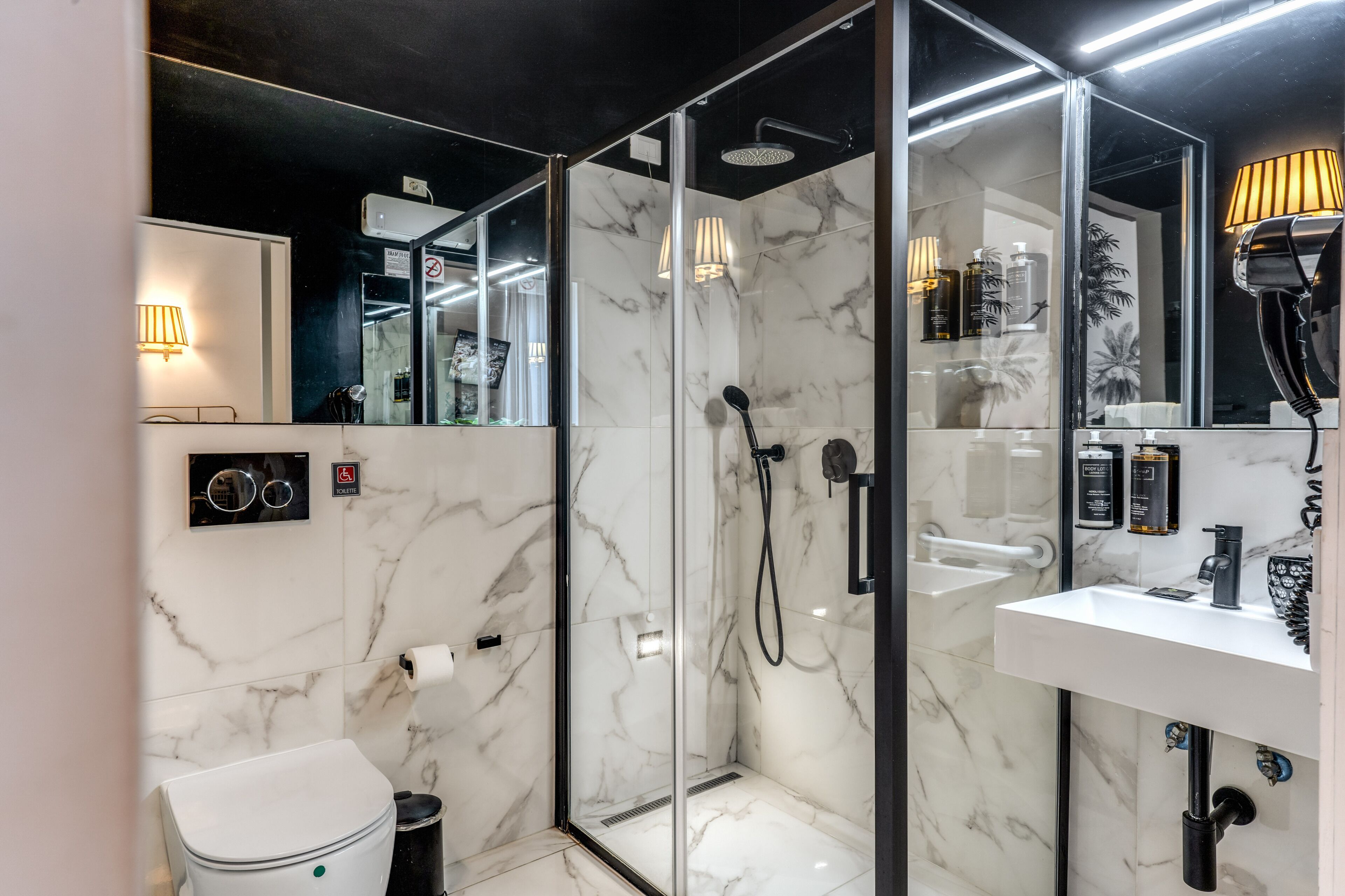 A modern bathroom with a glass-enclosed shower, a white sink, and a toilet.