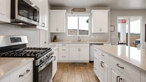 Una cocina moderna con armarios blancos, una estufa de acero inoxidable y un ventanal con vistas panorámicas.