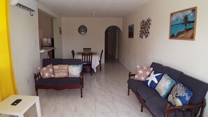 Uma sala de estar com sofá, mesinha de centro e um espaço de jantar com cadeiras e mesa.