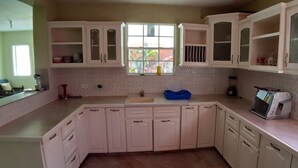 Uma cozinha com armários brancos, uma janela com vista e um micro-ondas na bancada.