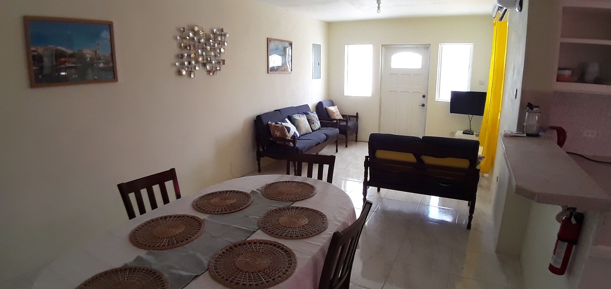 A dining area with a round table, chairs, and a sofa in the background.