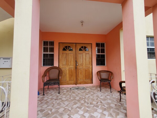 Una habitación con suelo de baldosas, dos puertas de madera y dos sillas.