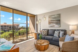 Relax in this stylish living room with a sofa, coffee table, and floor lamp, leading to a balcony with outdoor seating and a view.