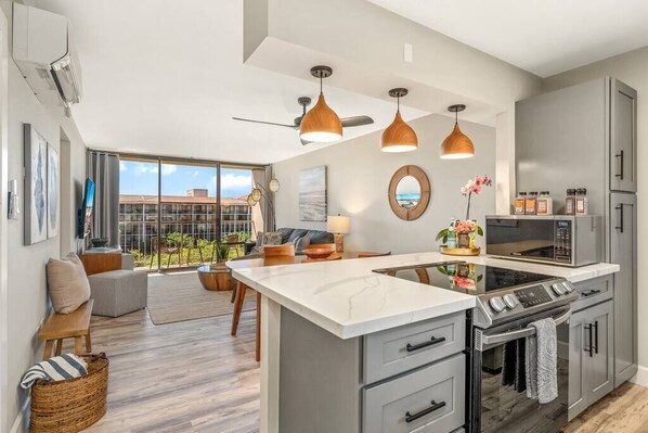 Enjoy meals in this well-equipped kitchen with a central island, stove, and oven, adjacent to a cozy dining area with a sofa and coffee table.