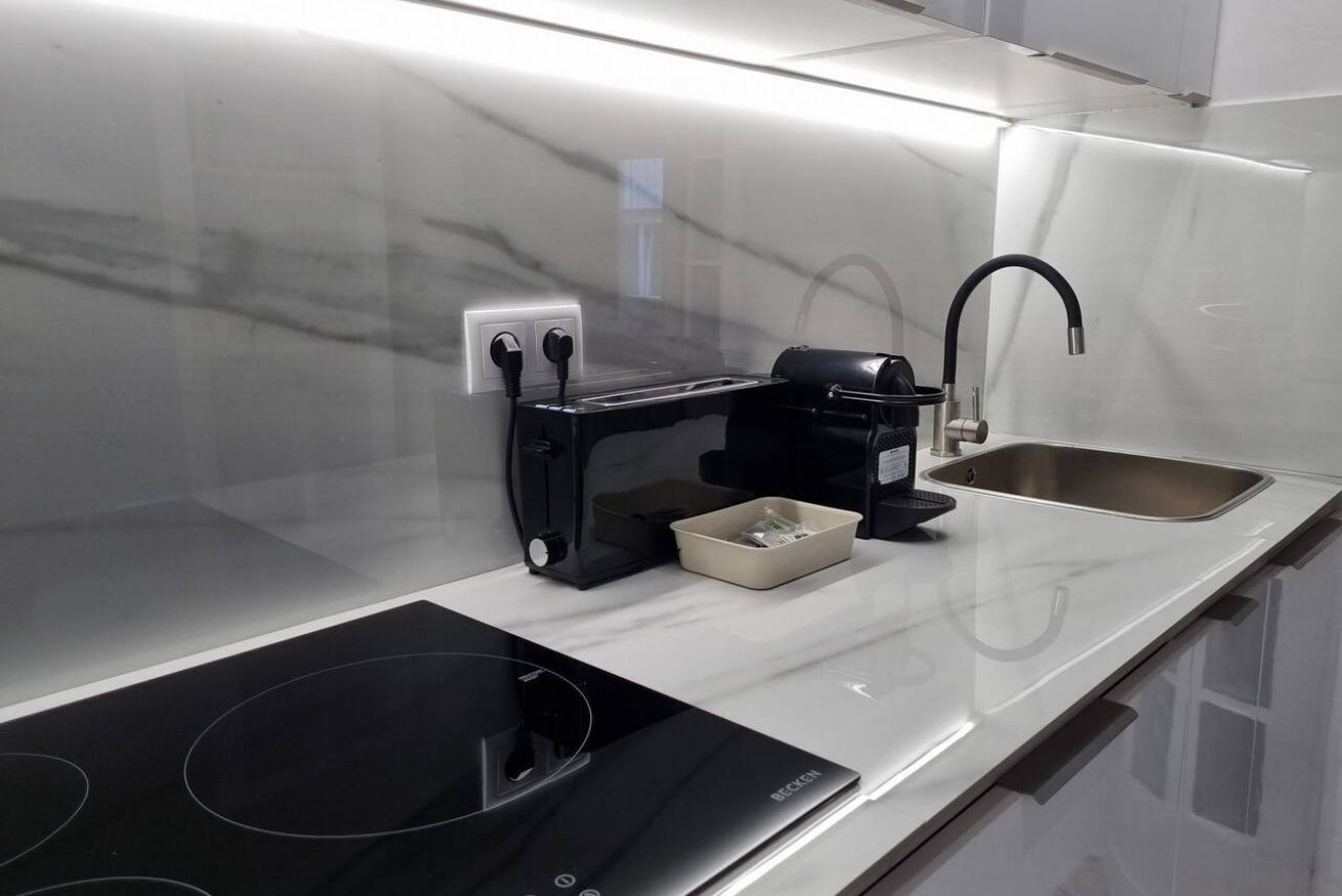Une cuisine moderne équipée d’une plaque de cuisson à induction intégrée, d’une machine à café et d  ’un évier.