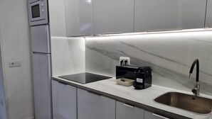 Eine moderne Küche mit integriertem Mikrowellenherd, einer Kaffeemaschine und einem Edelstahl-Spülbecken.
