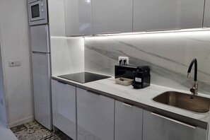 Una cocina moderna con microondas integrado, cafetera y pileta de acero inoxidable.