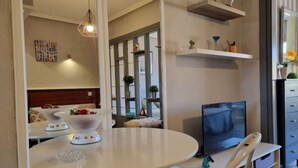 Een moderne woonkamer met een ronde eettafel, een flatscreen televisie en een bank.