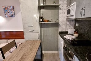 Une cuisine moderne avec une table à manger en bois, des appareils électroménagers intégrés et un crédence décorée.