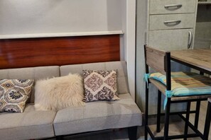 Un canapé avec des coussins à motifs, une chaise en bois avec un coussin rayé et une tête de lit en bois.