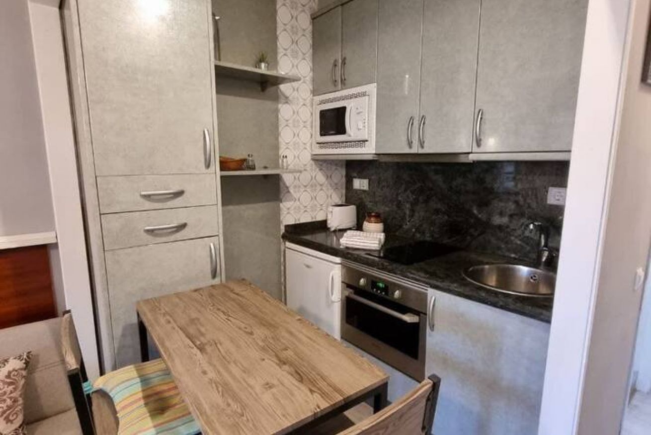 Cocina compacta con microondas, horno y lavaplatos.