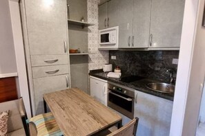 A compact kitchen with a microwave, oven, and sink.