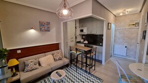 A compact living space with a sofa, a dining table, a kitchen area, and a small round table.