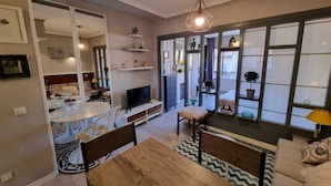 A modern living room with a wooden dining table, a TV, and a sofa.