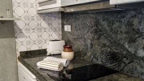 A kitchen with a marble countertop, a toaster, a stack of plates, and a washing machine.