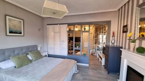 Een slaapkamer met een bed, nachtkastjes, een kaptafel, een spiegel en een open haard.