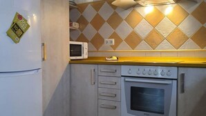 Une cuisine équipée d’un four à micro-ondes, d’un four traditionnel et d’un plan de travail jaune.