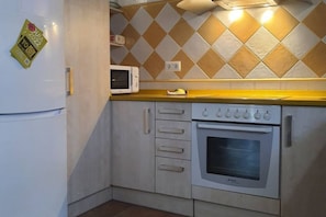 A kitchen with a microwave, oven, and a yellow countertop.