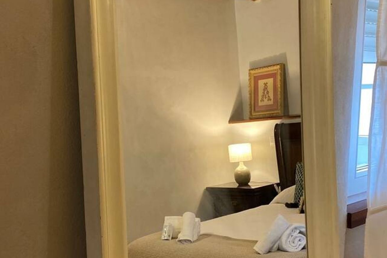 Une chambre d’hôtel avec un lit, une table de chevet avec une lampe, un tableau encadré au mur et une fenêtre avec des rideaux.