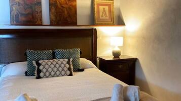 A neatly made bed with patterned pillows, a bedside lamp, and a framed picture above the headboard.