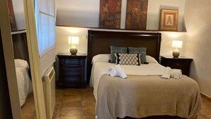 Une chambre d’hôtel avec un lit, deux tables de chevet, un radiateur et des œuvres d’art accrochées au mur.