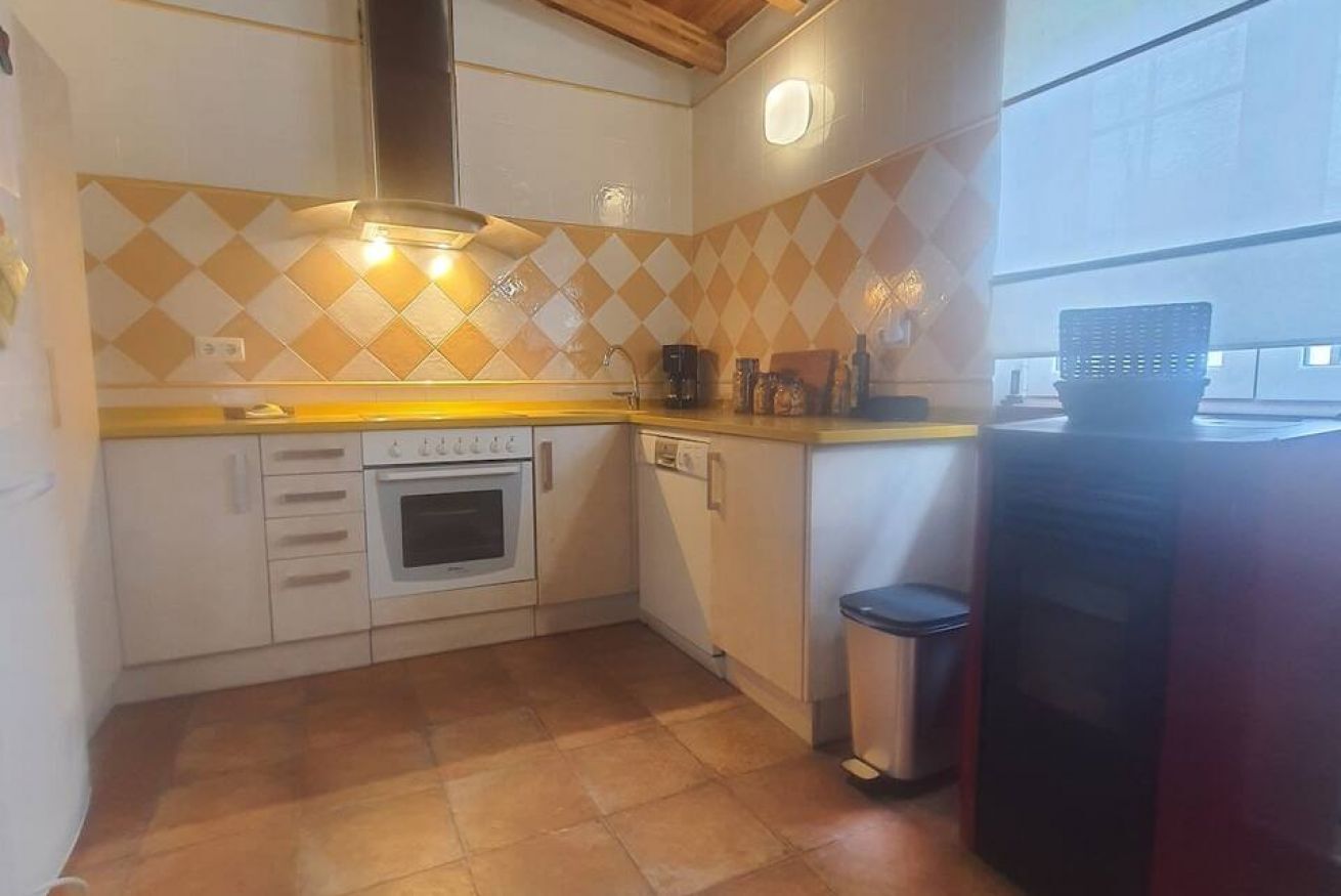 Une cuisine avec un plan de travail recouvert de carreaux, une cuisinière, un lave-vaisselle et une poubelle.