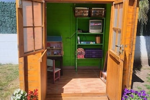 Eine kleine Holzhütte mit grüner Inneneinrichtung, einem Fernseher auf einem Regal und einer Tür, die nach draußen führt.