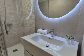 A bathroom with a white sink, a mirror, and a shower enclosure. - 154A: Central and Bright Apartment by R2R Consulting (Gijón)