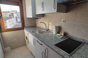 A compact kitchen with a built-in washing machine, a sink, and a countertop with a built-in induction cooktop. - 154A: Central and Bright Apartment by R2R Consulting (Gijón)