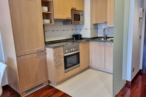 A kitchen with wooden cabinets, a microwave, a stove, and a sink.