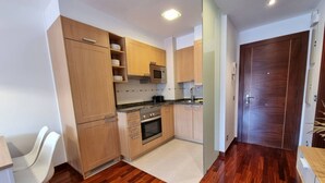 A compact kitchen with wooden cabinets, a microwave, an oven, and a sink.