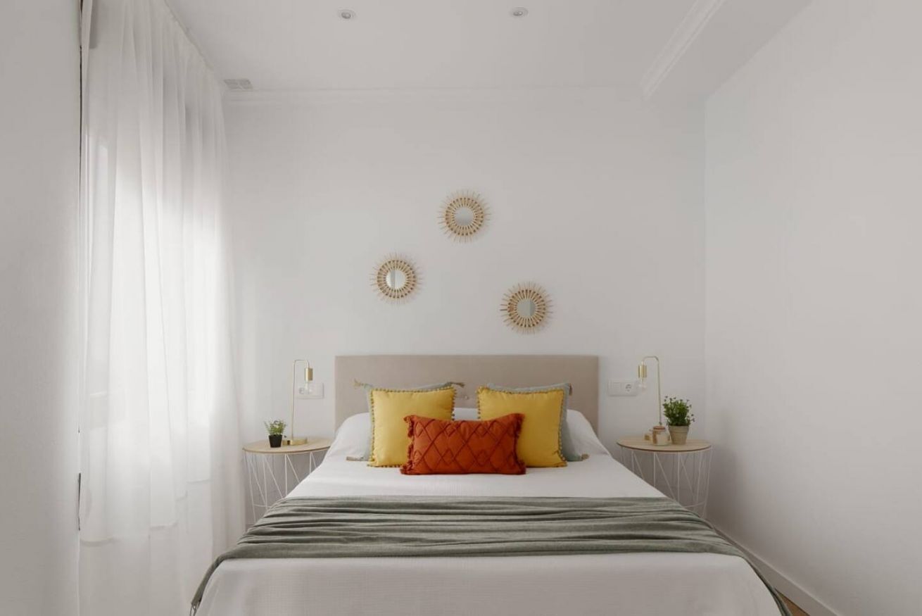 Un dormitorio con cama, dos mesitas de noche, cabecero y tres adornos en la pared.