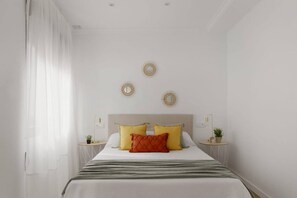 Een slaapkamer met een bed, twee nachtkastjes, een hoofdeinde en drie decoratieve items aan de muur.