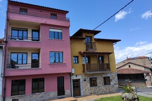 A multi-story building with balconies, a stone base, and a clear sky. - 17B01 - Apartamento Caravia (Caravia)