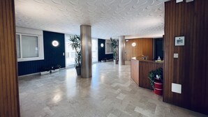 A spacious lobby with a reception desk, large potted plants, and a modern ceiling design. - Modern Apartment Near the Beach in Jesolo, Italy (Jesolo)