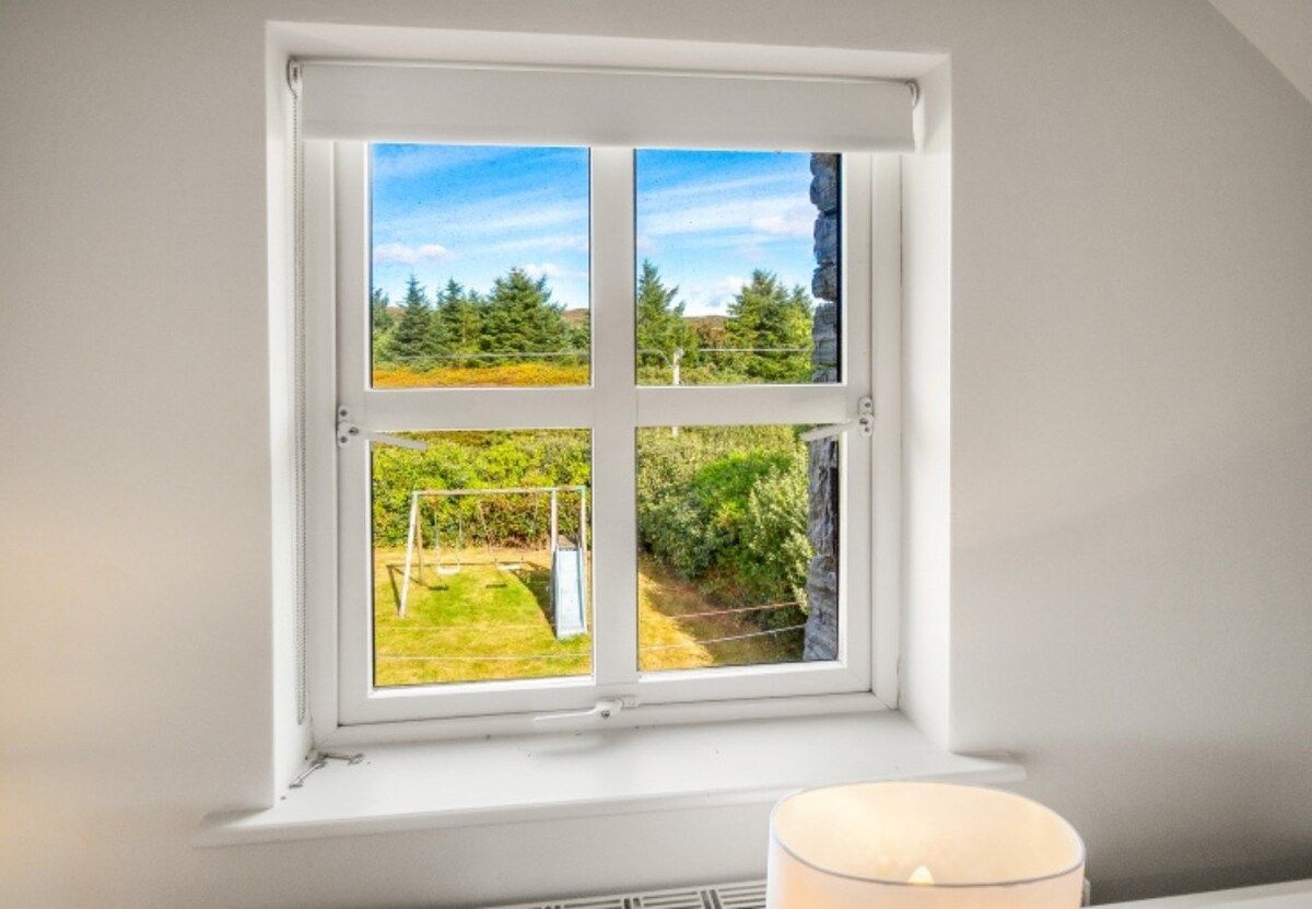 Janela com vista para um jardim e árvores.