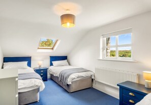 A bedroom with two beds, a skylight, a window with a view, and a radiator.