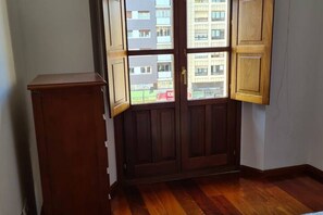 Une pièce d’angle avec un meuble en bois, une porte en bois dotée de panneaux de verre et une vue sur un bâtiment, visible à travers la porte.
