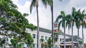 A modern building with a white facade, multiple windows, and a green roof. - Townhouse OAK Hotel Grand Cikarang (Cikarang)