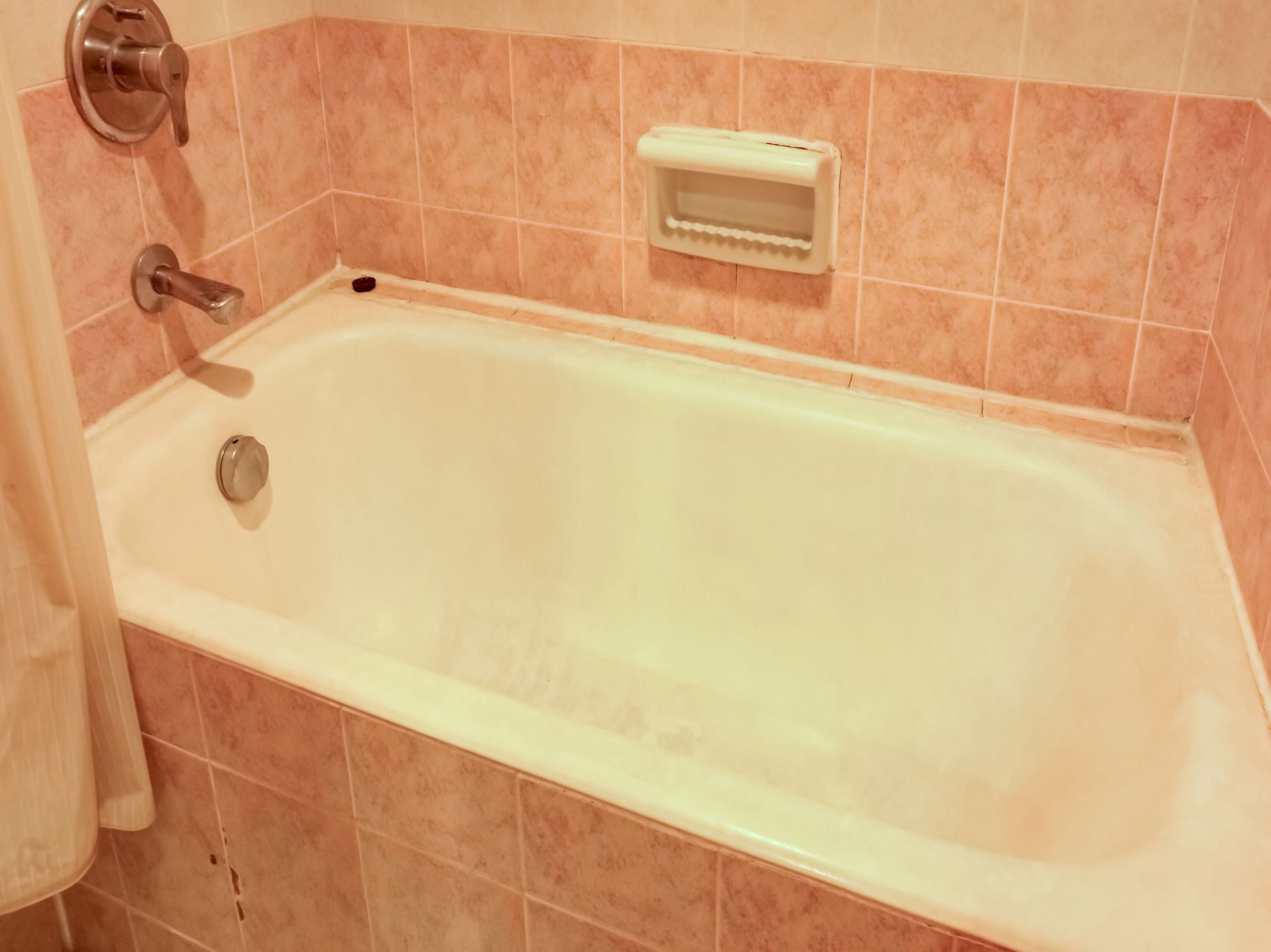 Un bagno con una vasca, un water e un portasapone a parete.
